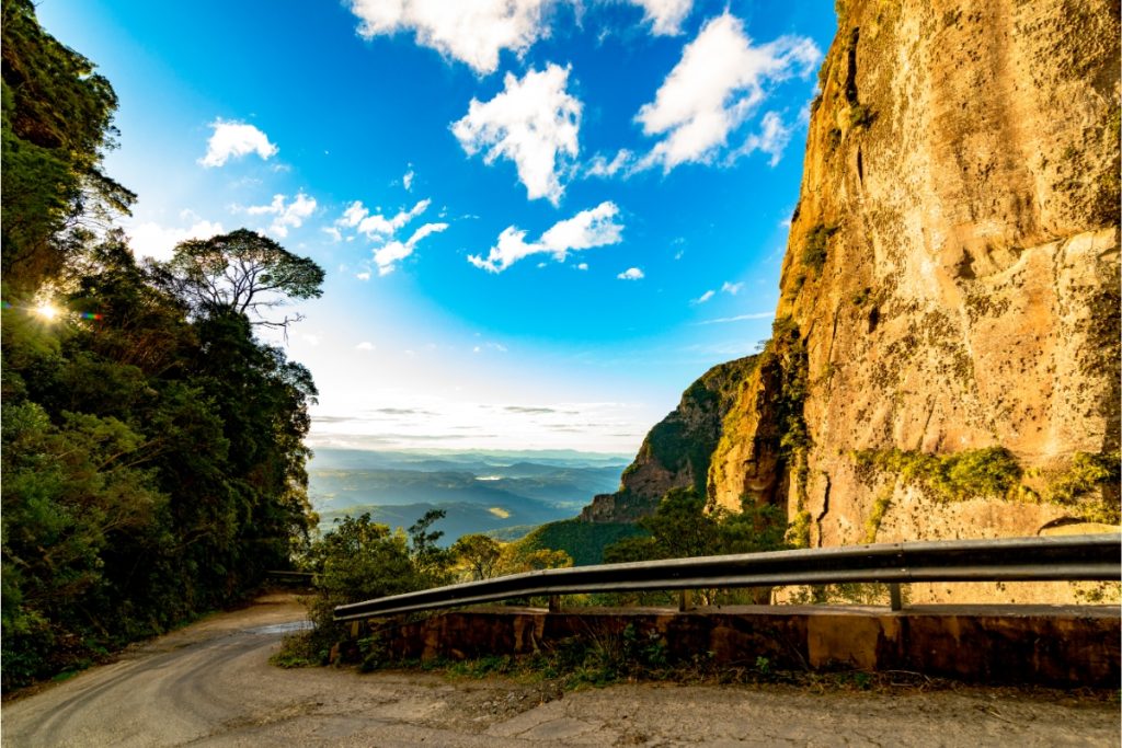 Estrada de terra na Serra do Corvo. 
Caminho  ladeado por rochas.
Ao fundo céu azul com nuven e florestas.
Viagem segura e tranquila .
seguro auto para 
